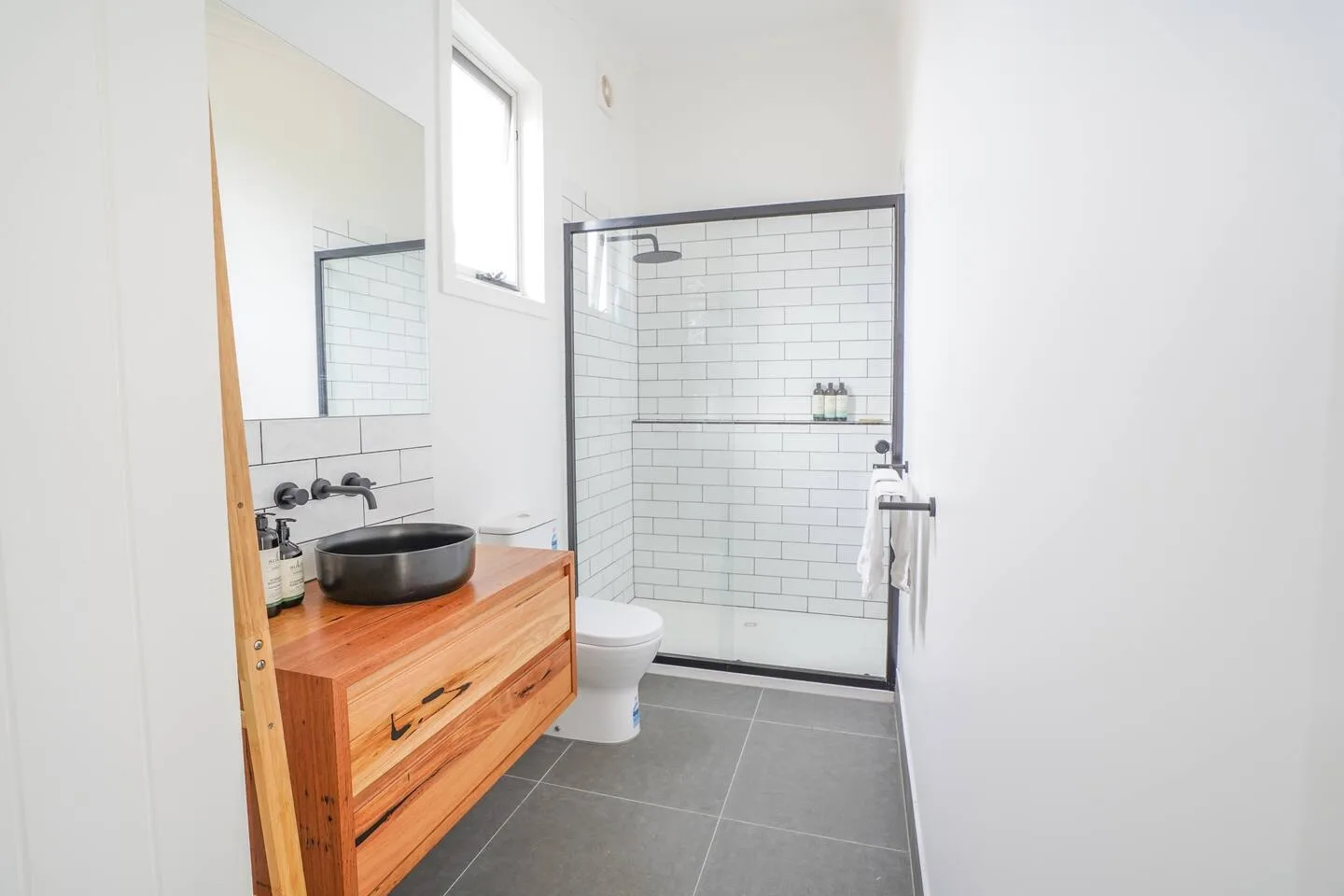 El elegante baño cuenta con un moderno mueble de lavabo y una ducha de techo.