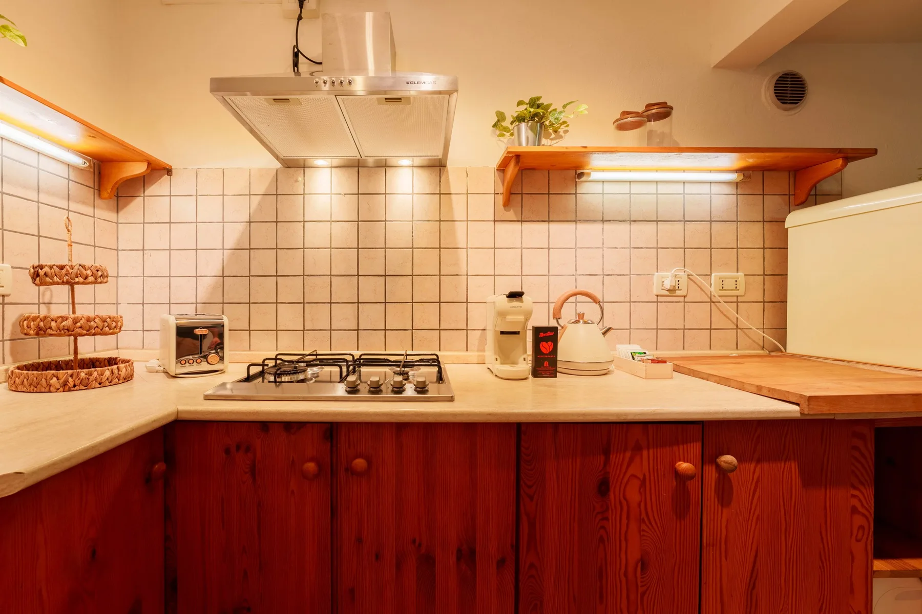 A kitchen with a tiled backsplash, countertop, and stovetop.