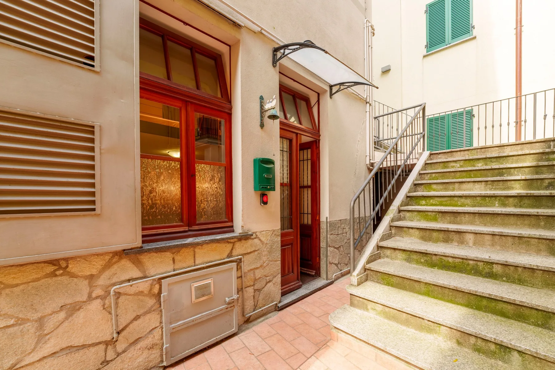 An exterior entrance with red-framed windows beside a staircase.