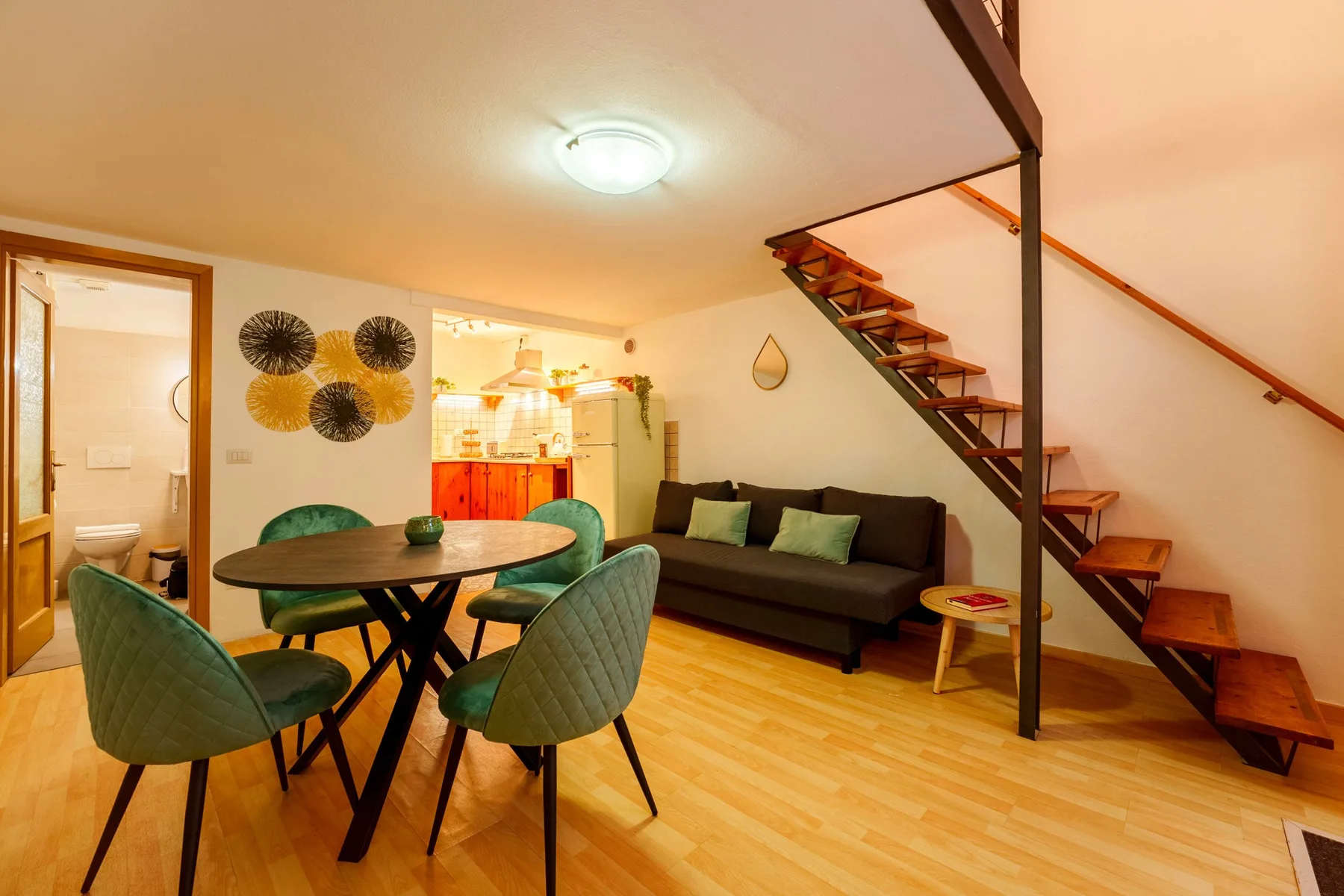 A living room with seating, a dining table, and a staircase.