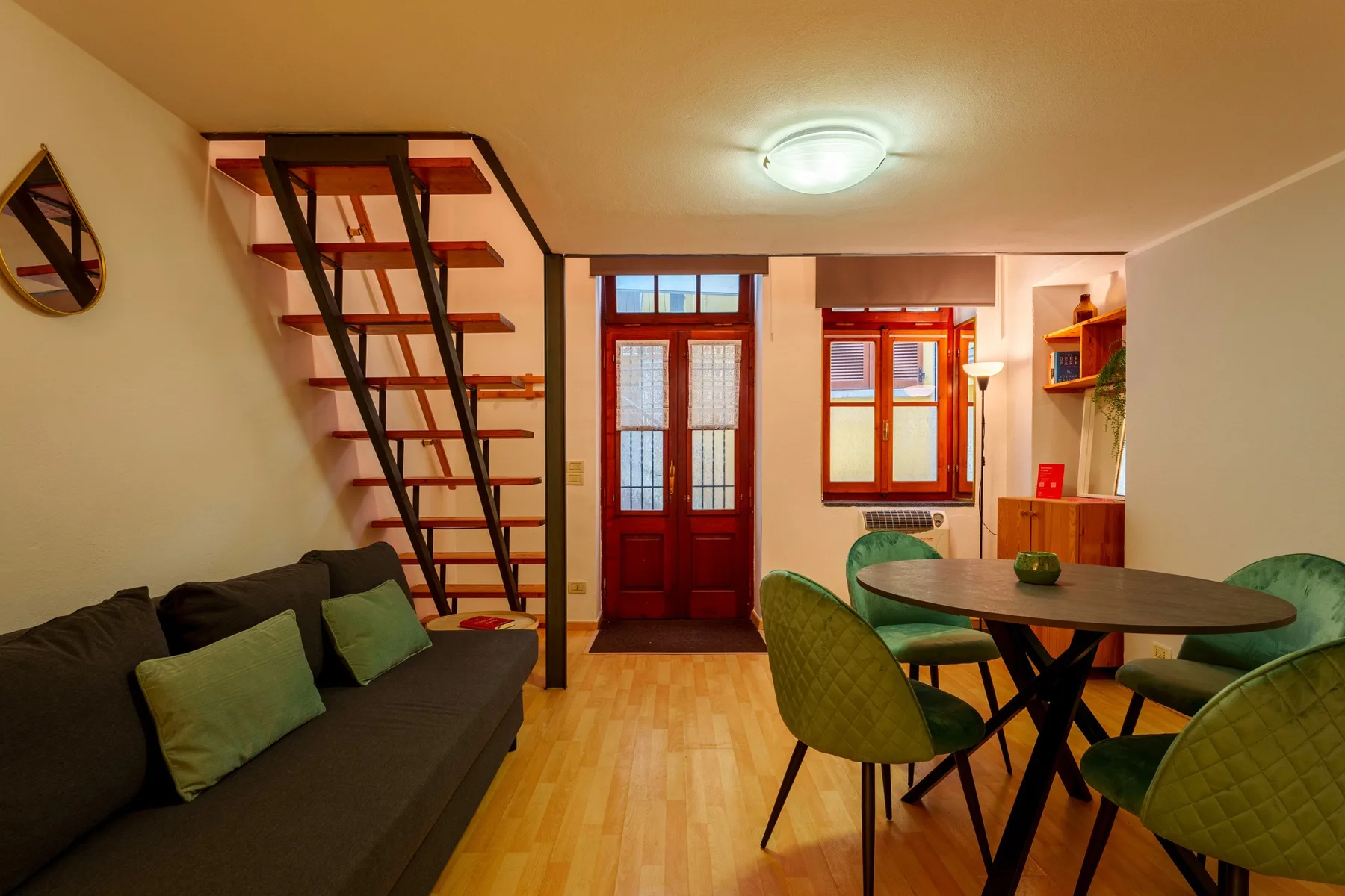 A furnished living and dining area with a dark sofa, table, and chairs.