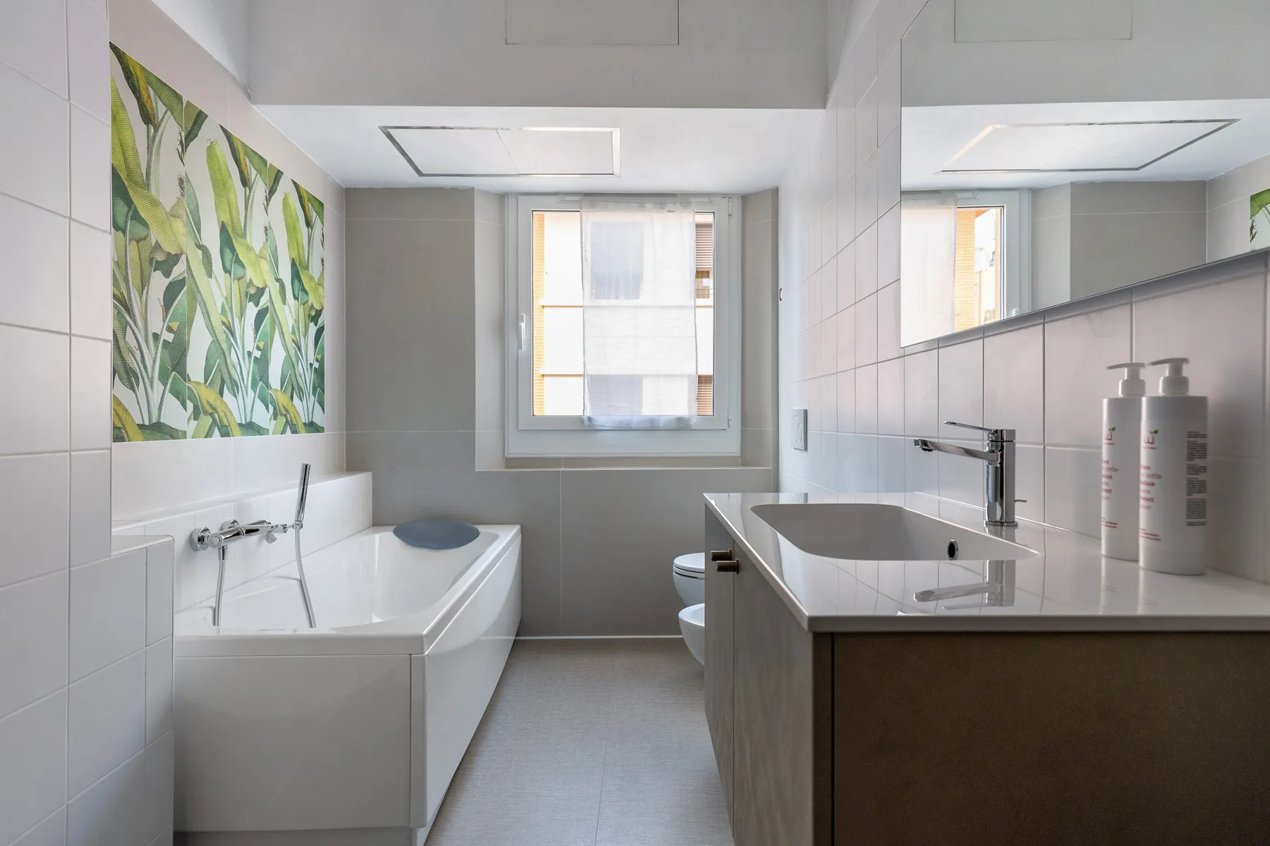 A bright bathroom with a bathtub, sink, and large wall mirror.