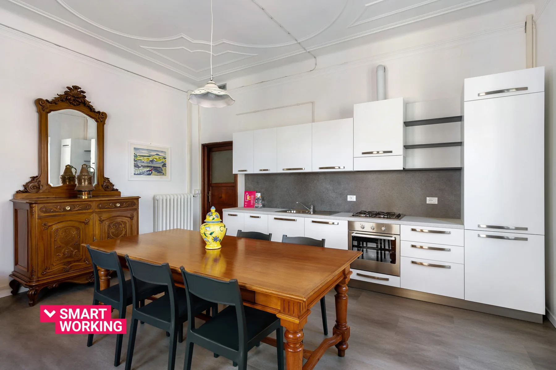 A dining area with a wooden table beside a white kitchen.