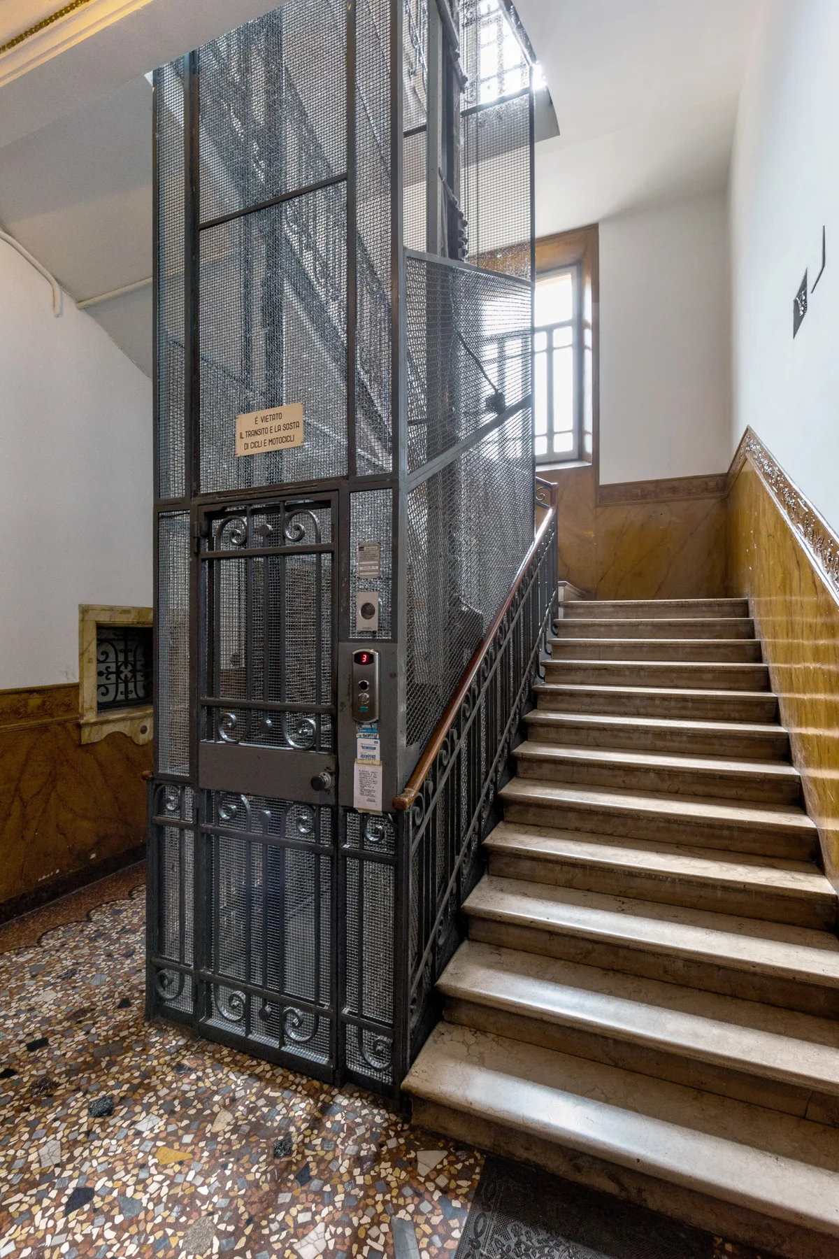 A stairwell with a metal-caged elevator beside the stairs.