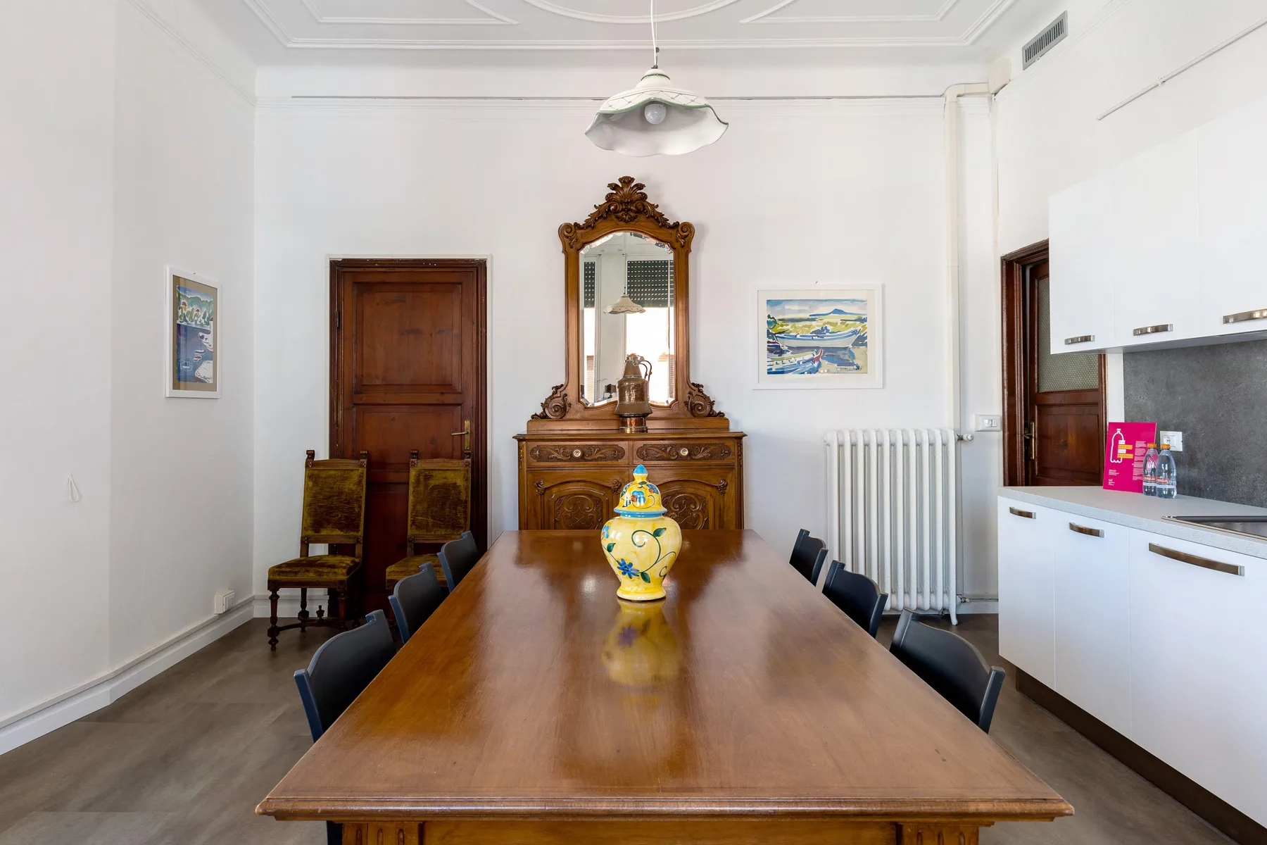A dining room with a long wooden table and a decorative mirror above a sideboard.
