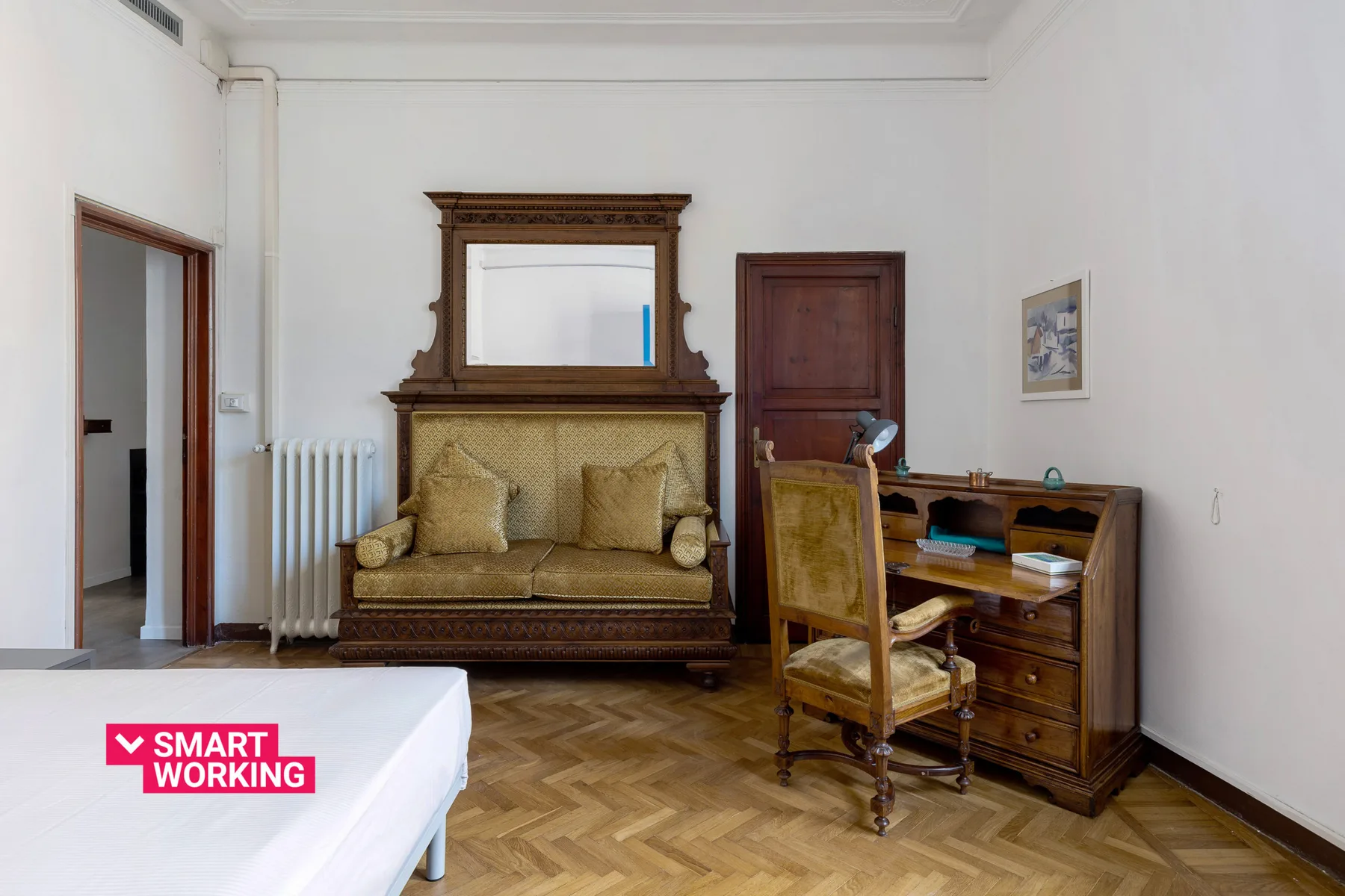 A bedroom with a bed, an ornate headboard, and a wooden desk.