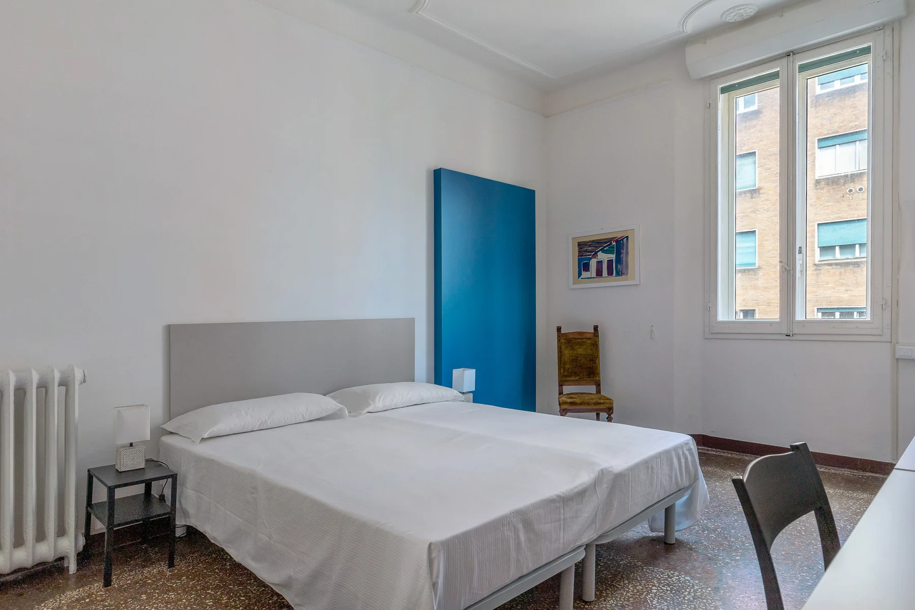 A bedroom with a double bed, a blue door, and a window.