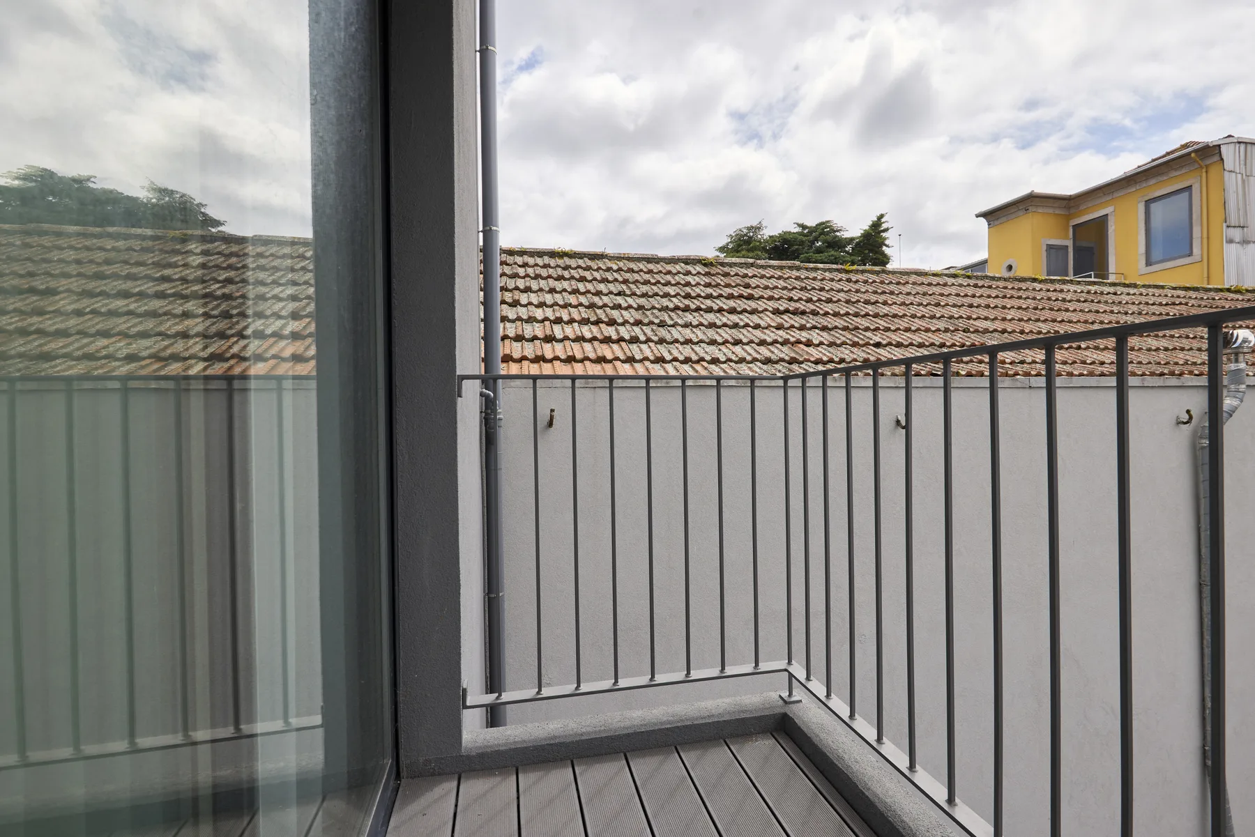 A small balcony with metal railings overlooks tiled rooftops.