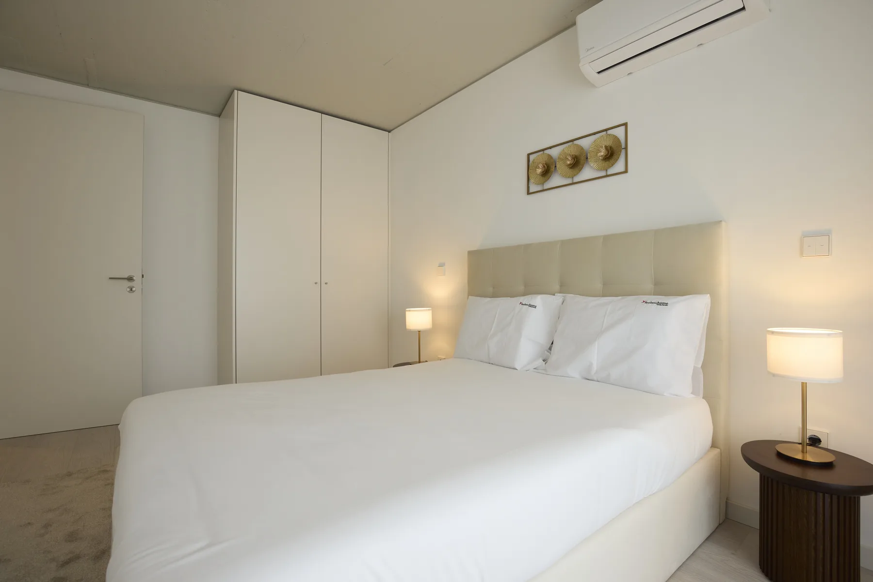 A bedroom with a neatly made bed and bedside lamps.