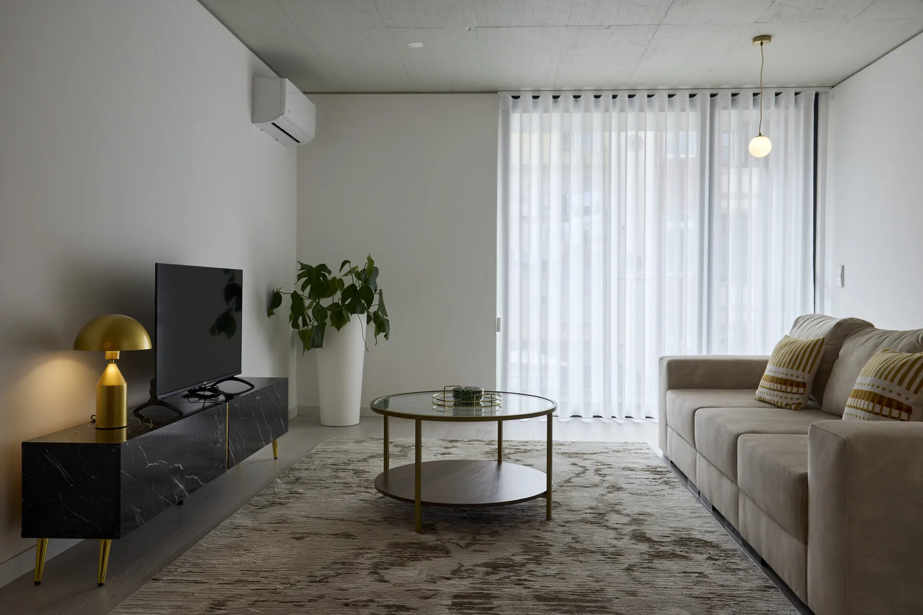 A living room with seating, a television, and sheer curtains.