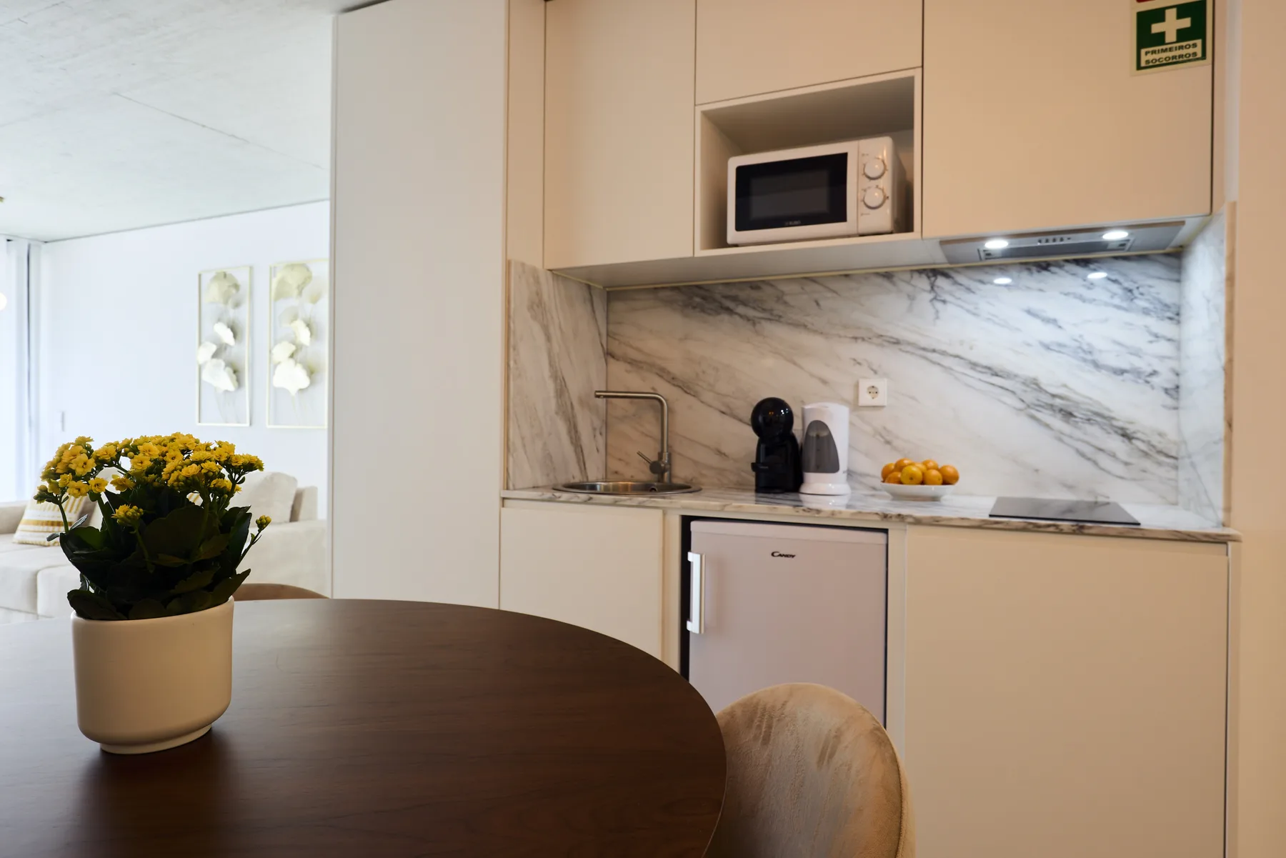 A kitchen with pale cabinetry, a marble-patterned backsplash, and a dining table.