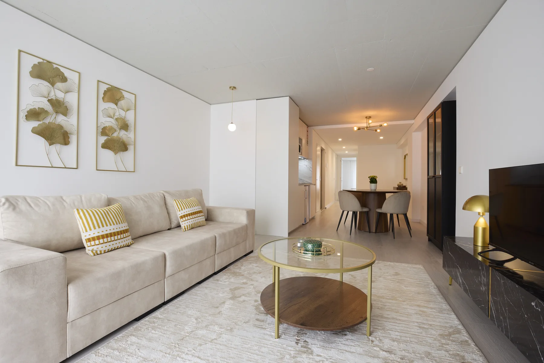 A modern living room with seating, a round coffee table, and a dining area.