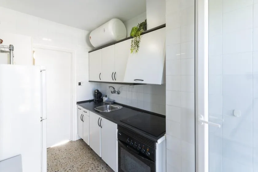 A compact kitchen with white cabinets, dark countertops, and a built-in oven.