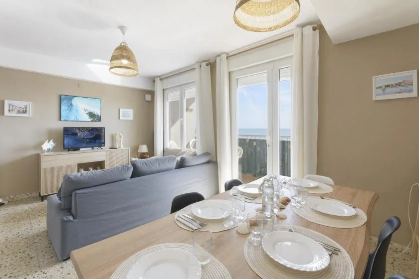 A bright living and dining area with seating beside tall windows.