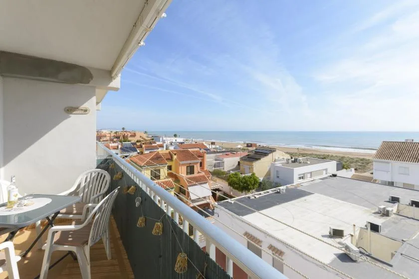 A balcony overlooks coastal buildings and the sea under a clear sky.