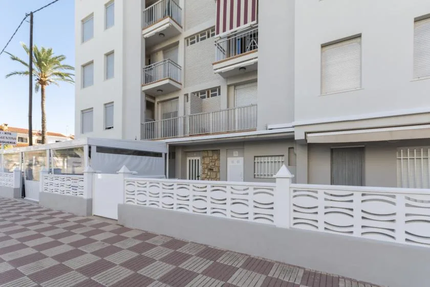 Apartment building exterior with balconies, windows, and a patterned sidewalk.