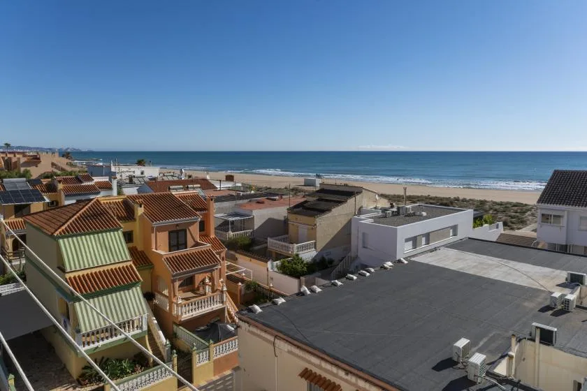 Coastal neighborhood with rooftops and the sea visible beyond.