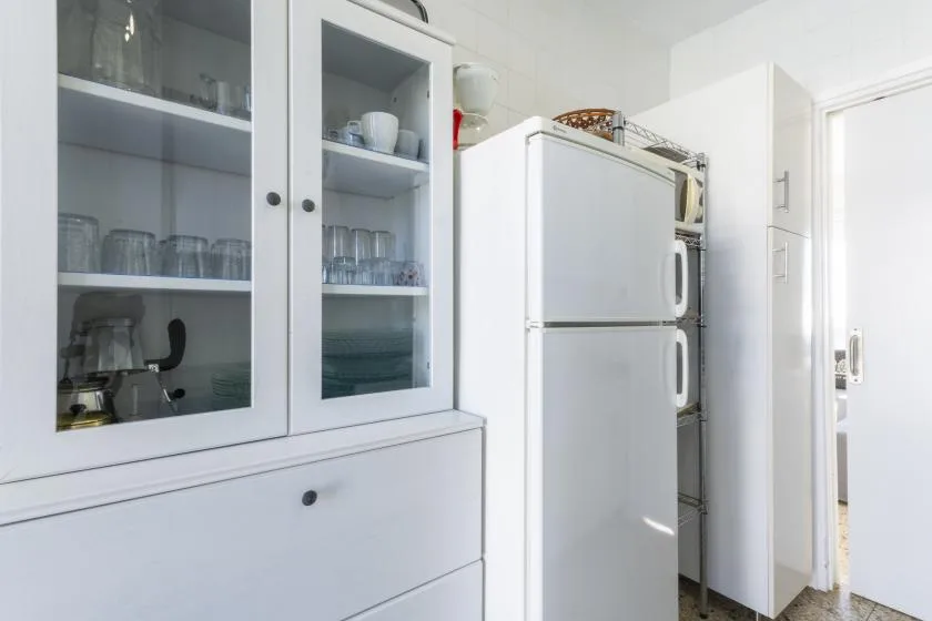 A bright kitchen with white cabinets and a refrigerator.