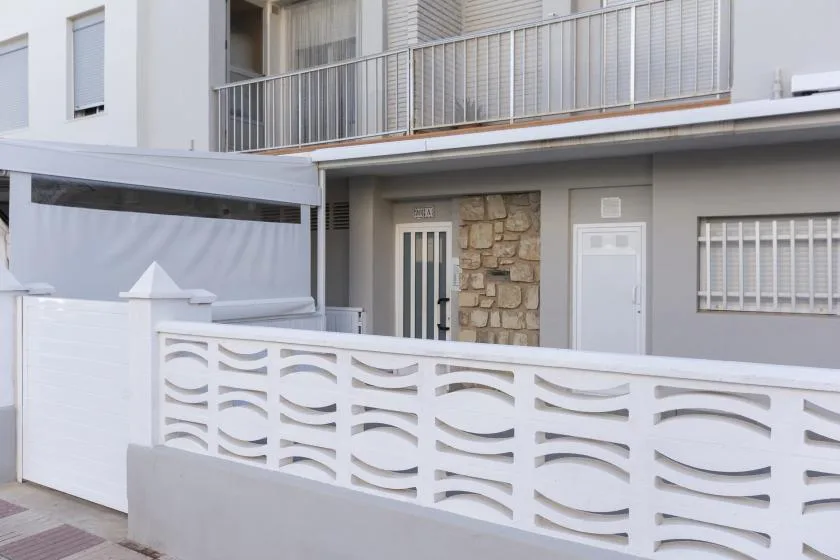 Exterior view of a building entrance with a white decorative fence in front.