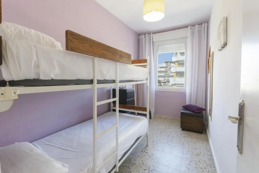 A bedroom with bunk beds and a window overlooking nearby buildings.