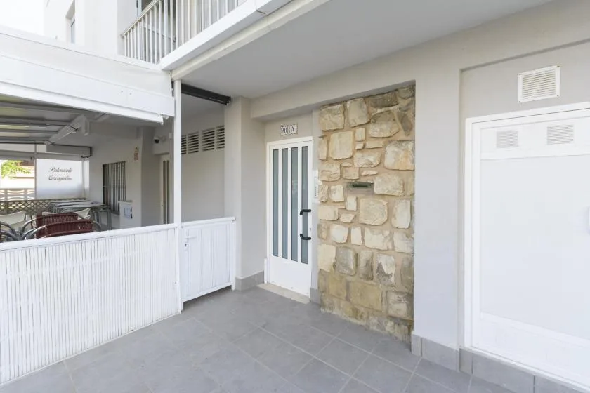 A covered outdoor entrance with a white door beside a stone wall.