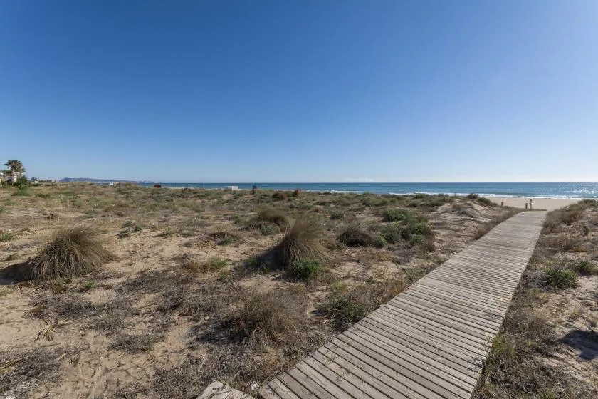 A wooden boardwalk crosses sandy dunes toward the shoreline.