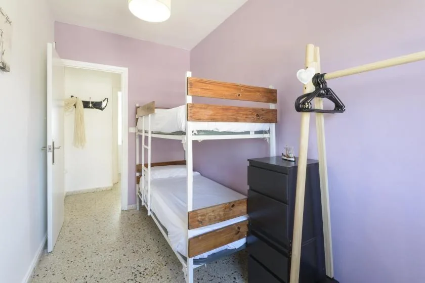 A bedroom with a bunk bed, a black dresser, and lavender walls.
