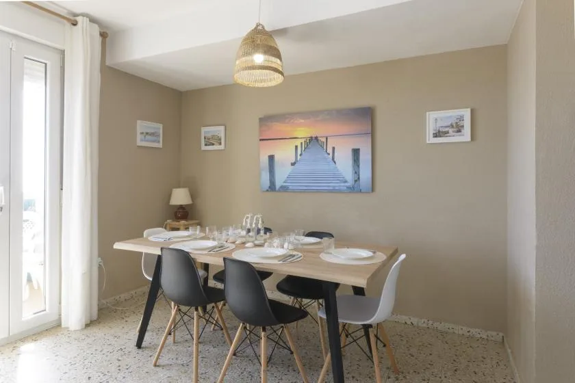 A dining area with a set table and chairs beneath a pendant light.