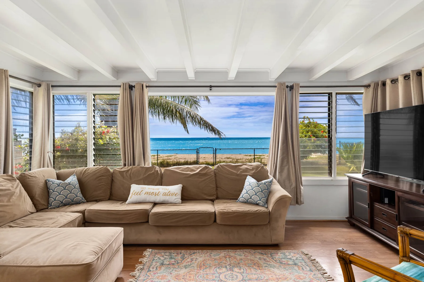 A living room with a large sectional facing windows that overlook the ocean.