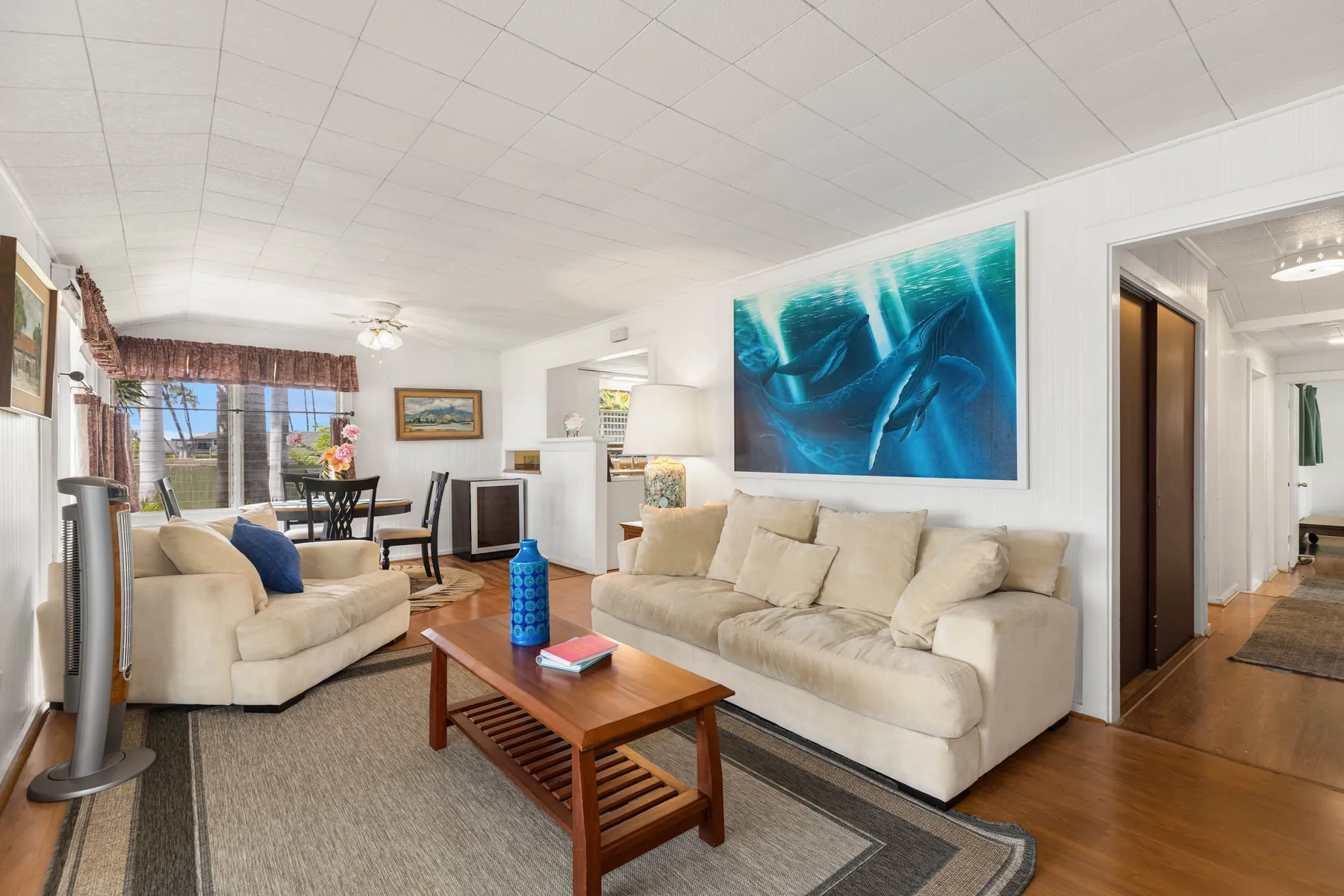 A bright living room with seating, a coffee table, and large blue artwork.