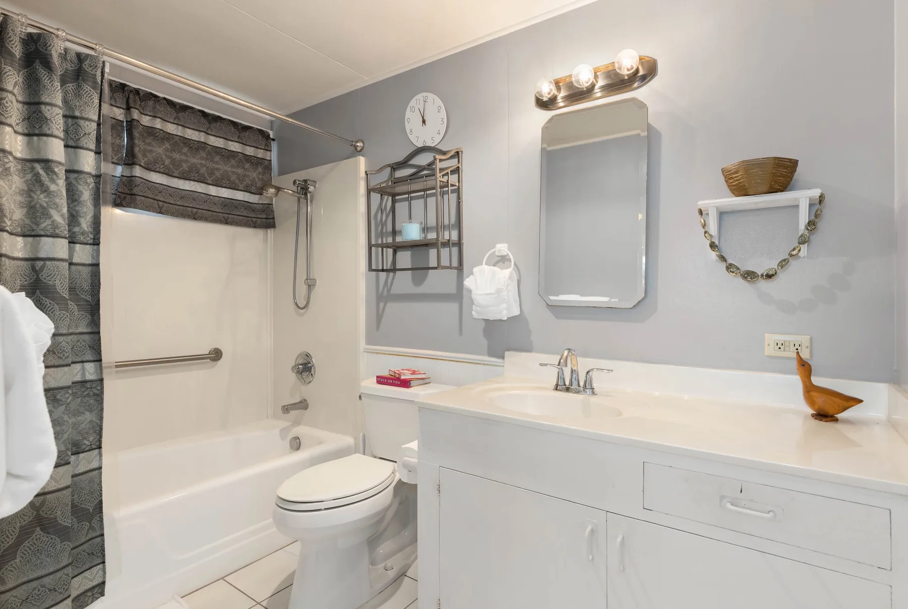 A bathroom with a bathtub, toilet, and sink beneath a wall mirror.