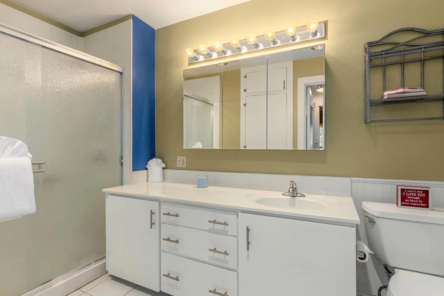 A bathroom vanity with a wide mirror and a glass shower.