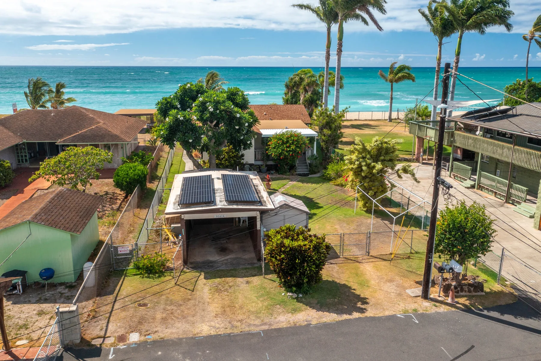 Aerial view of a coastal property with buildings, trees, and the ocean beyond.