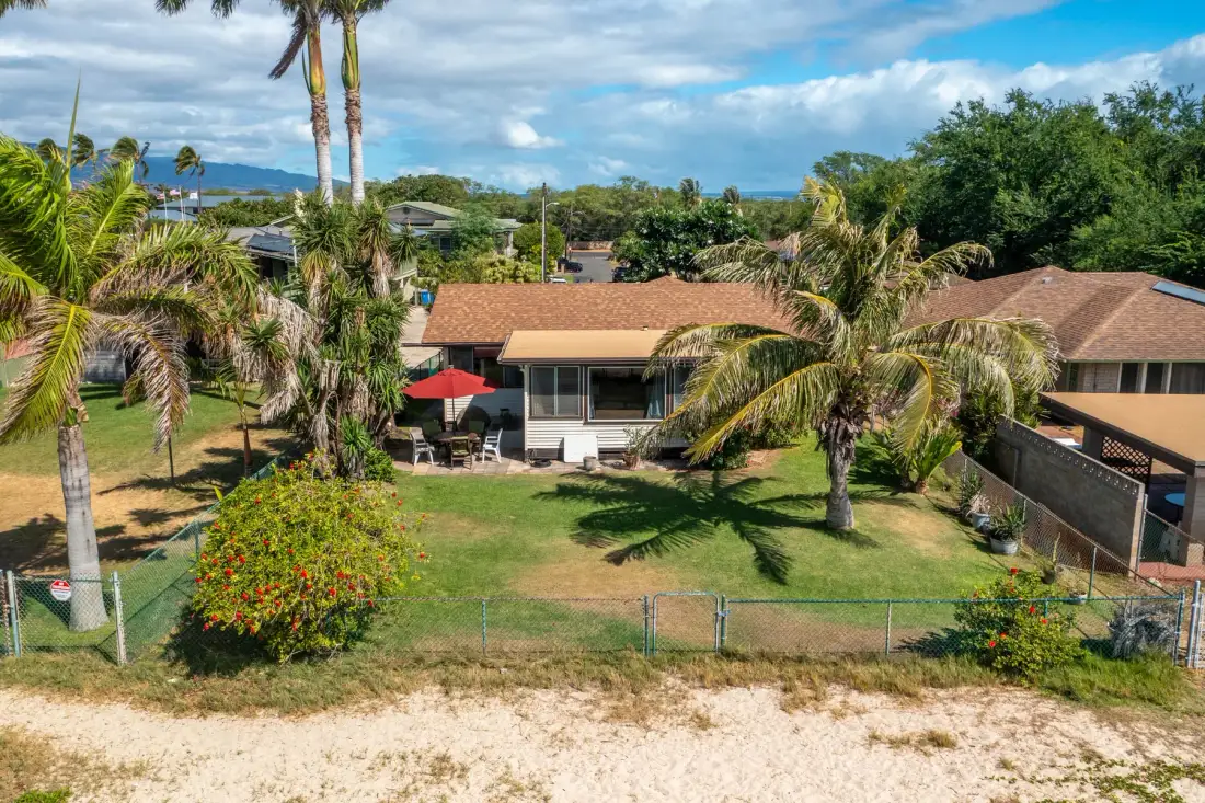 Aerial view of a house and green lawn with palm trees.
