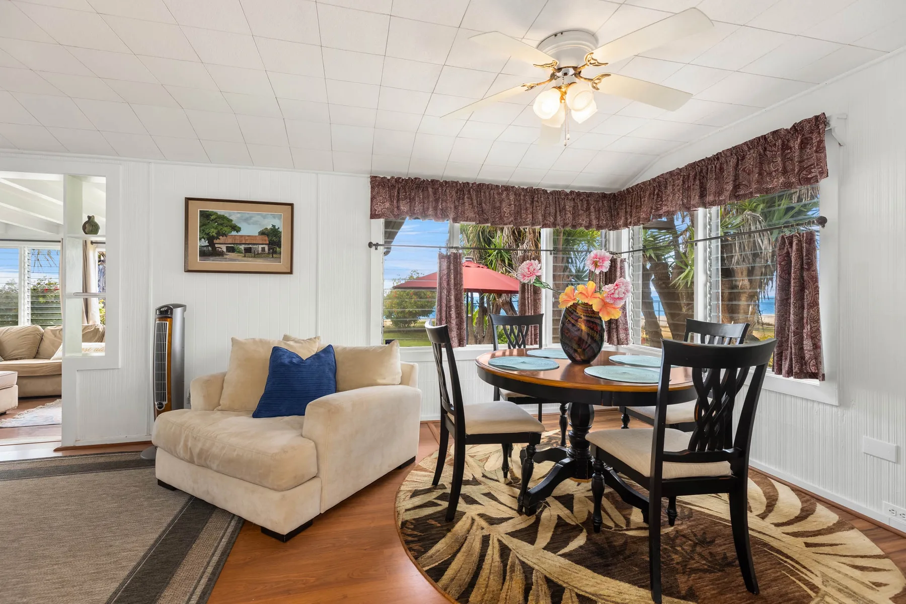 A bright dining area with a round table, dark chairs, and large windows.