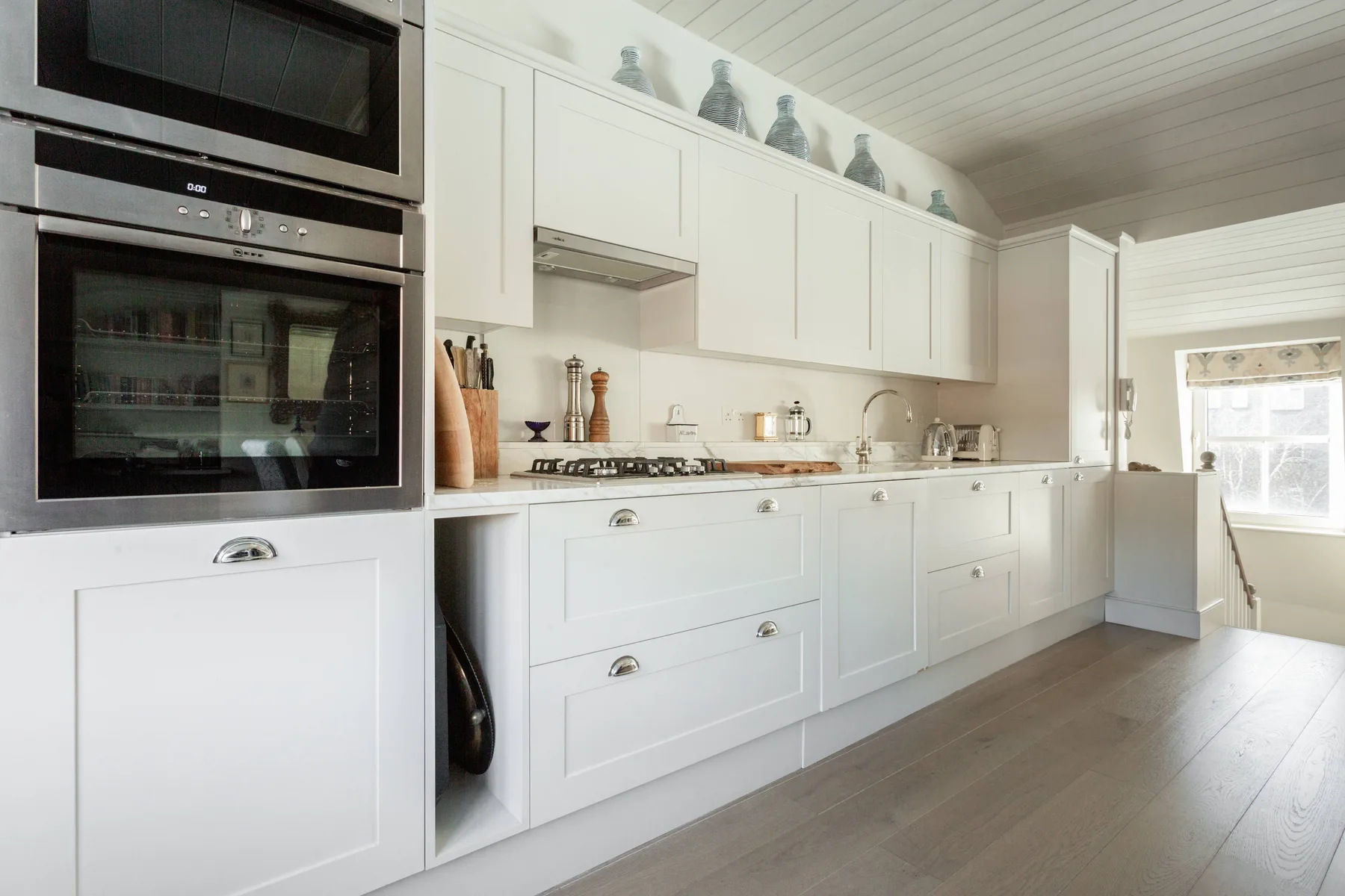 A bright kitchen with white cabinetry, countertop appliances, and a built-in oven.
