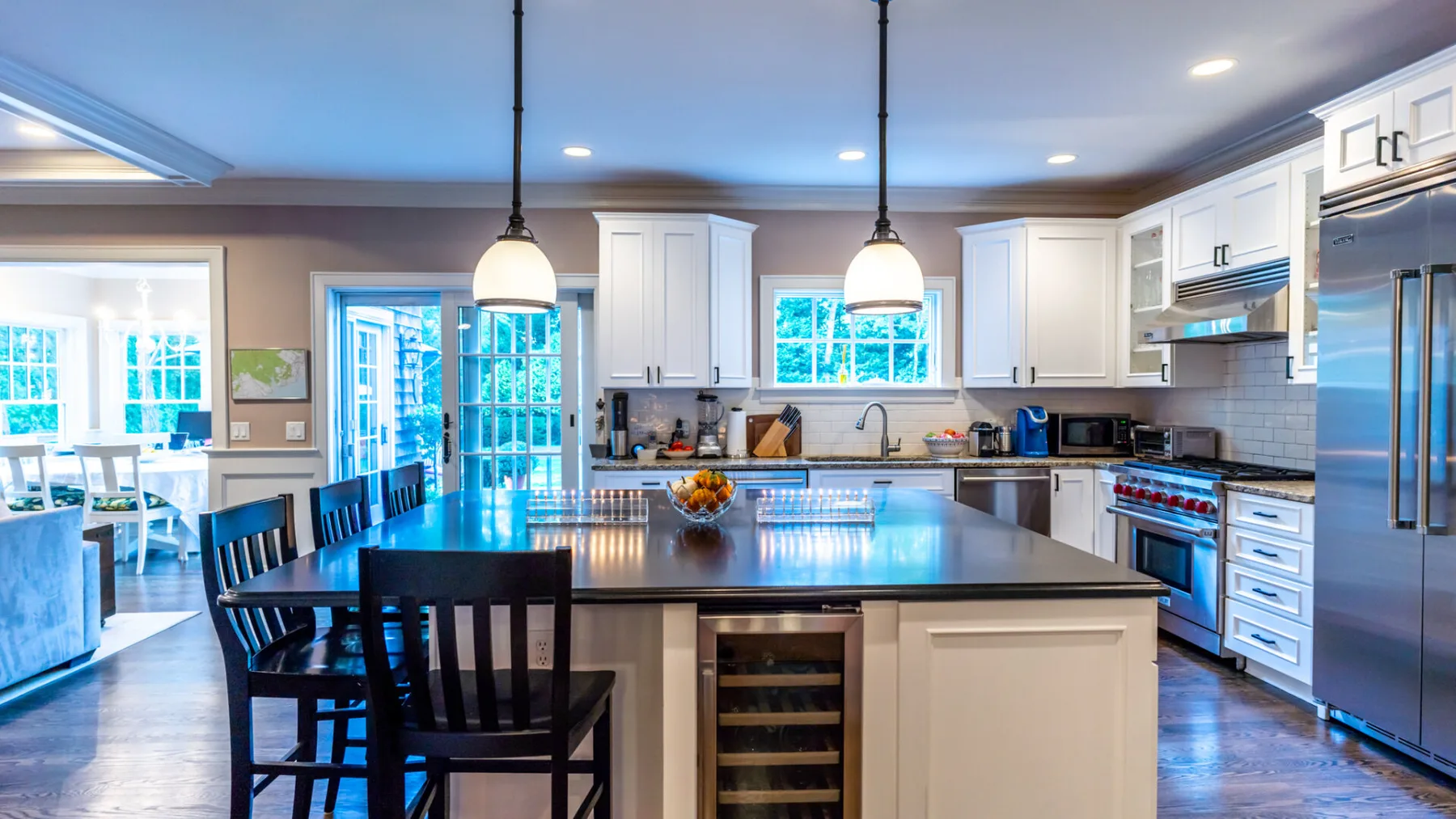 A bright kitchen features a large central island with dark seating.