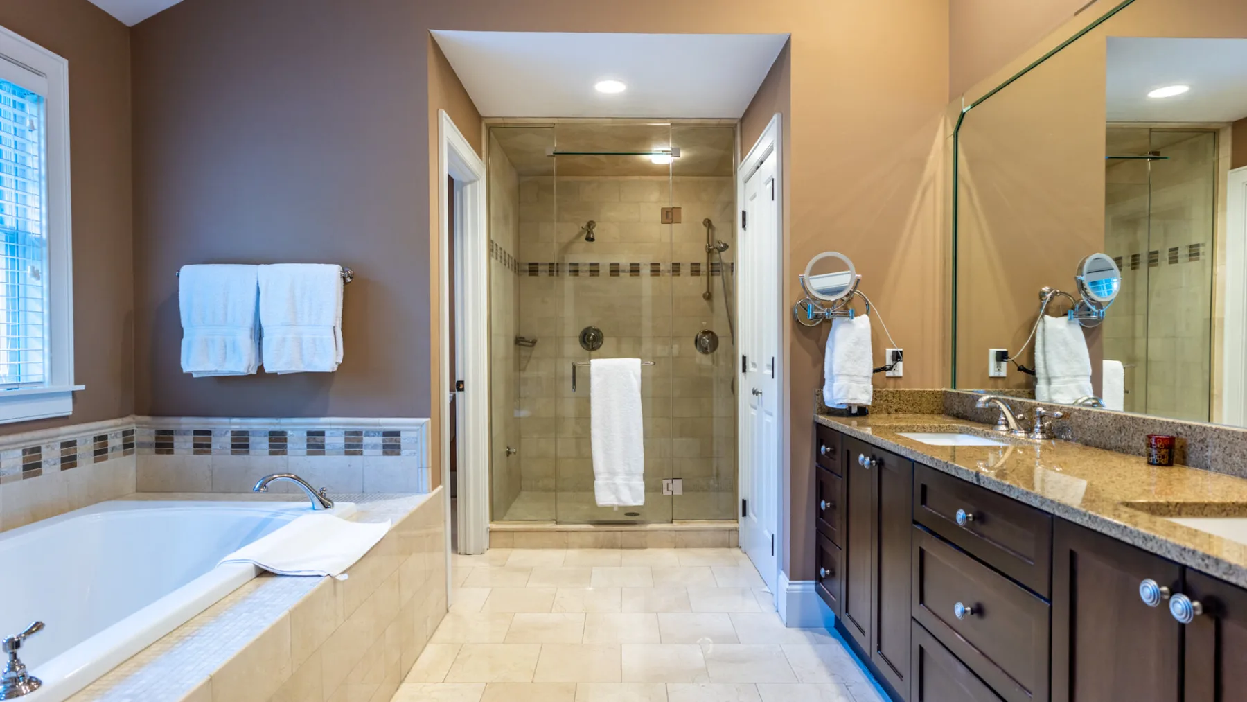 A bathroom with a bathtub, glass shower, and long vanity.