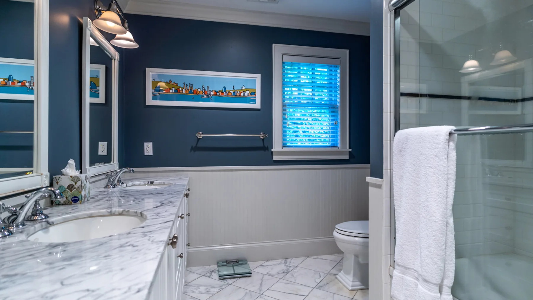 A bathroom with a marble-look vanity, toilet, and glass shower.