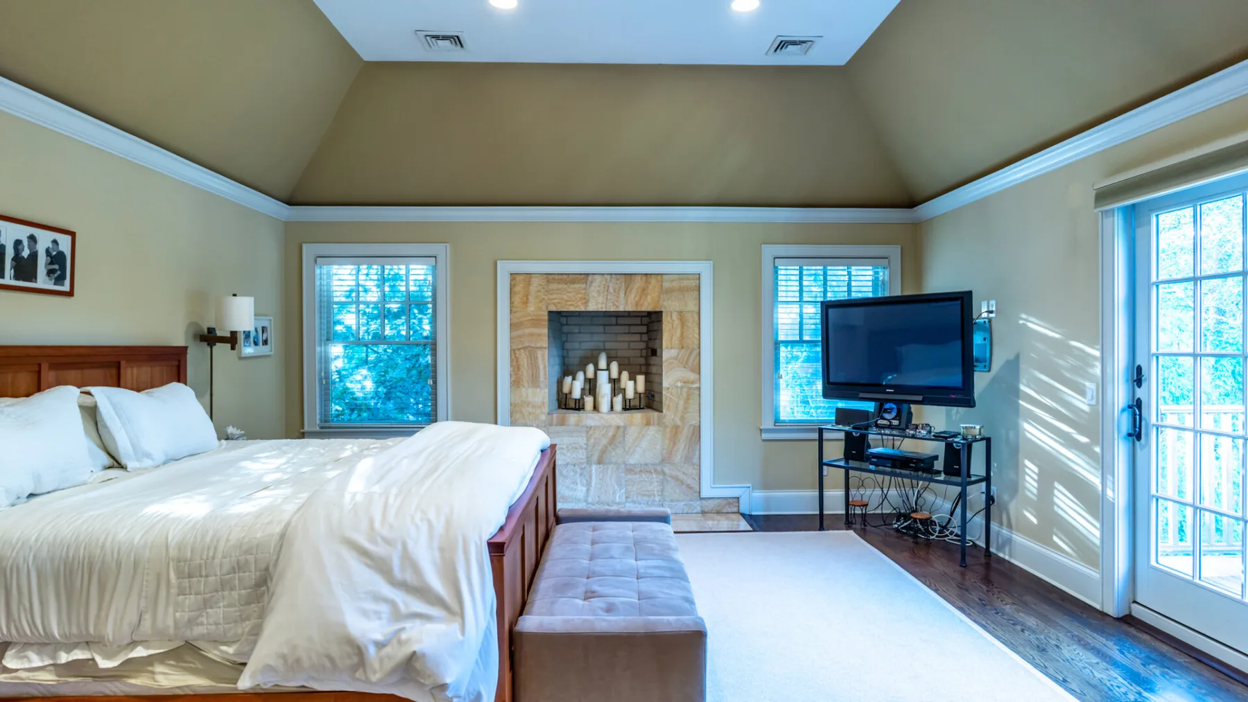 A bright bedroom with a bed, a fireplace, and a television.