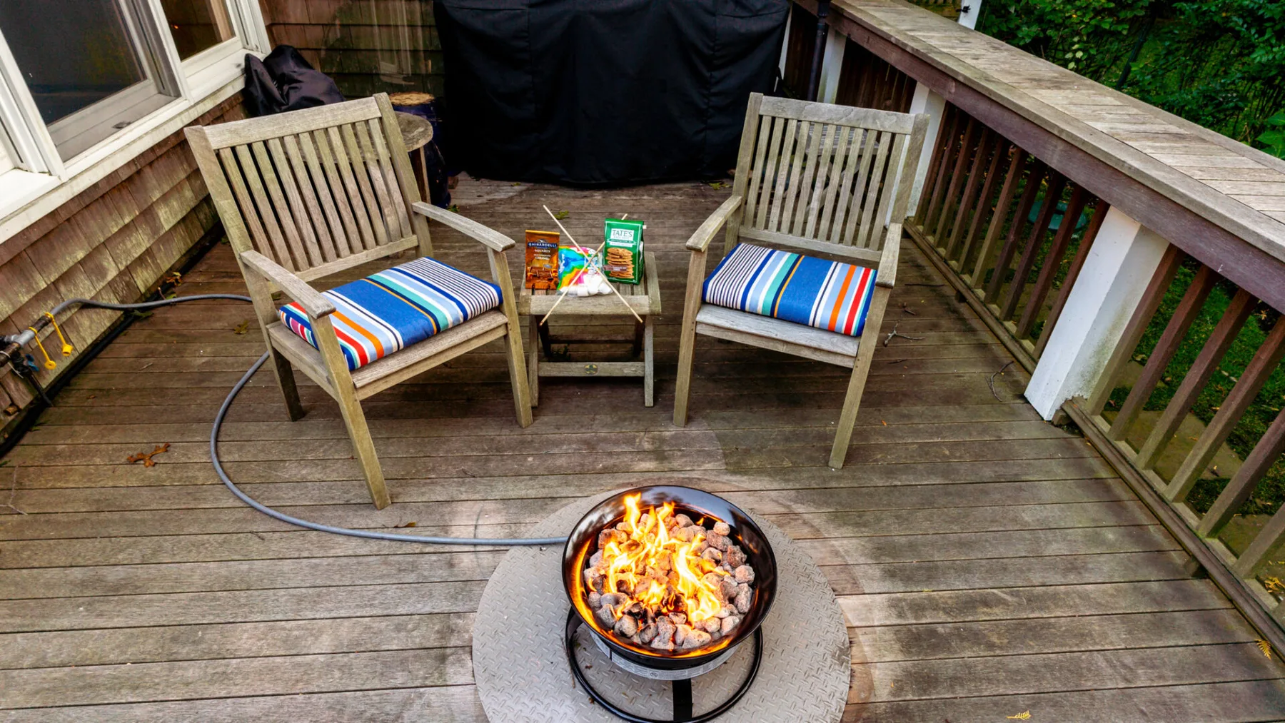 A wooden deck with outdoor seating and a burning fire pit.