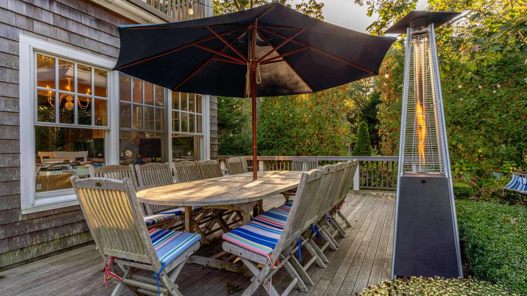 A wooden outdoor dining area with a large umbrella and patio seating.