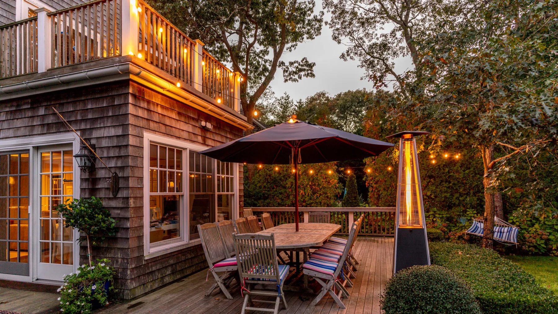 An outdoor deck with a dining table, seating, and a large umbrella.