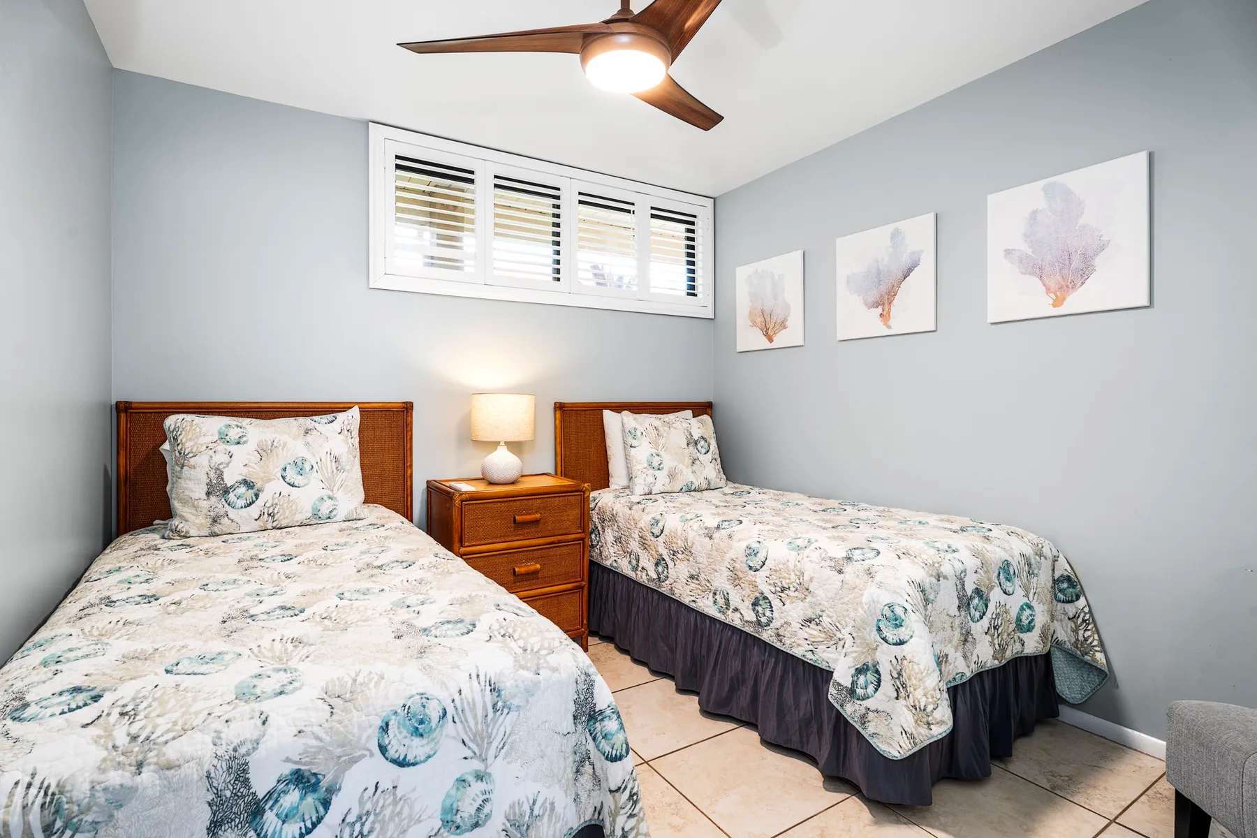 Un dormitorio con dos camas vestidas con ropa de cama floral y un ventilador de techo.