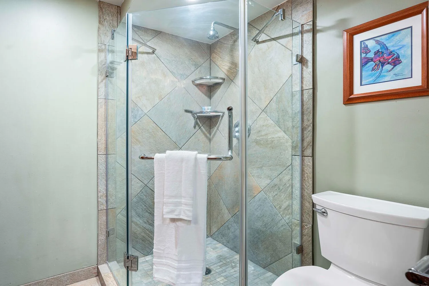 Un baño con azulejos, ducha de vidrio e inodoro.