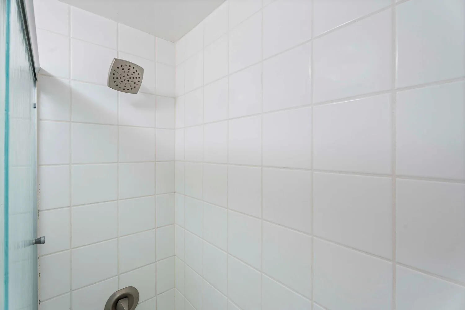 Una ducha alicatada con un cabezal fijado a la pared.