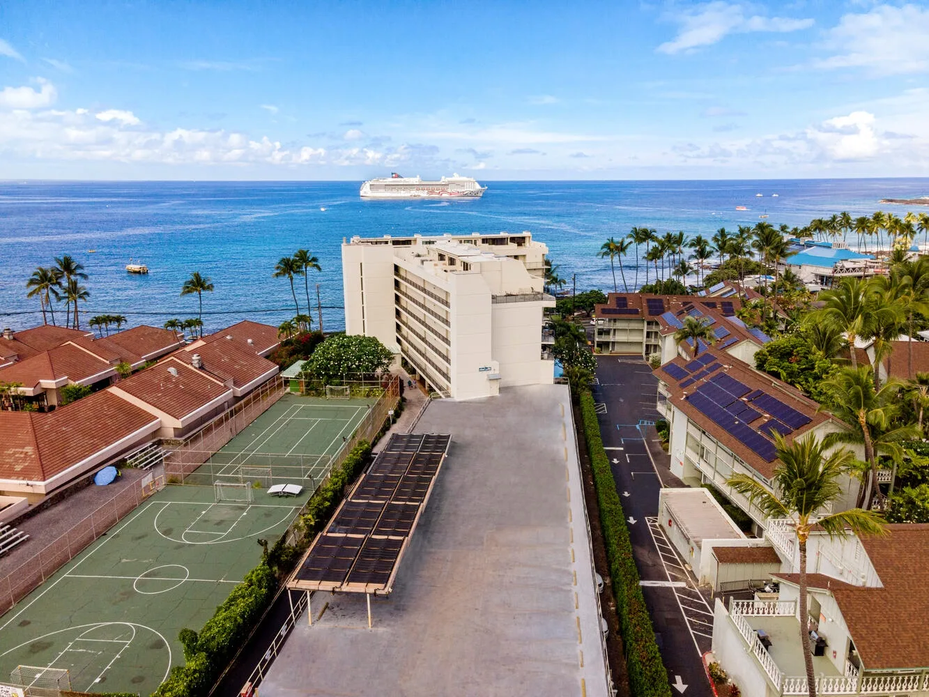 Vista aérea de edificios costeros y una cancha deportiva junto al océano.
