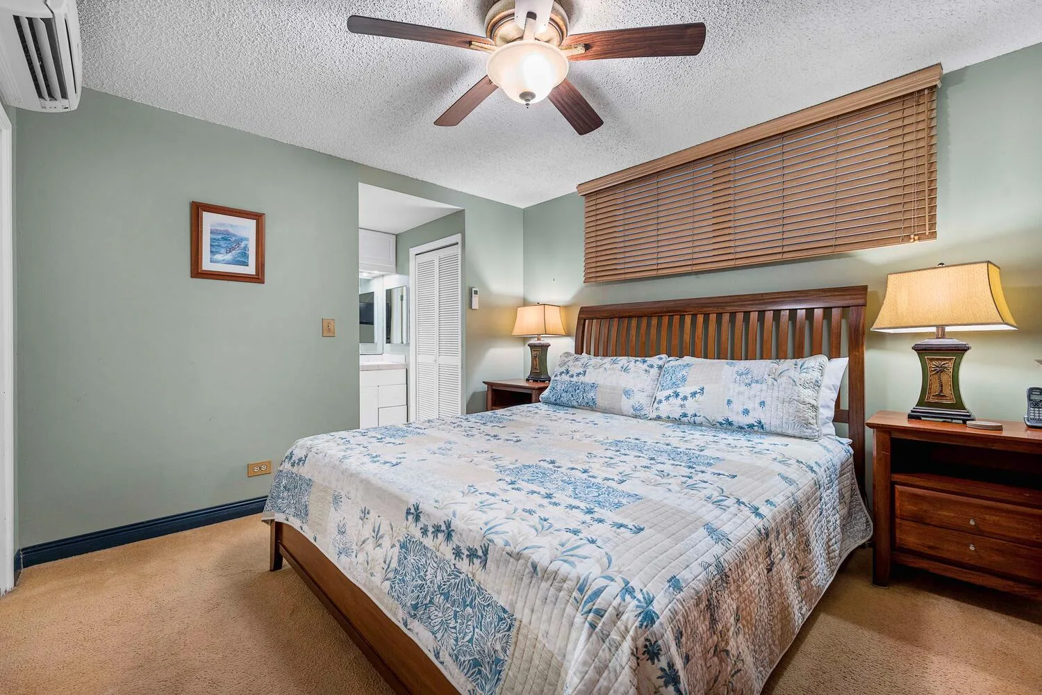 Un dormitorio con una cama de madera, ropa de cama azul estampada y lámparas de mesilla.