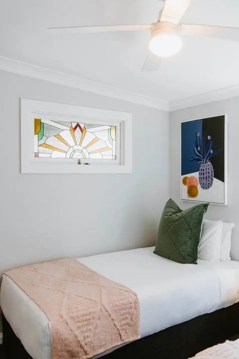 A bedroom with a neatly made bed and colorful artwork on the walls.