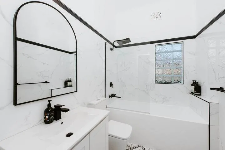 A bright bathroom with a bathtub, sink, and large wall mirror.